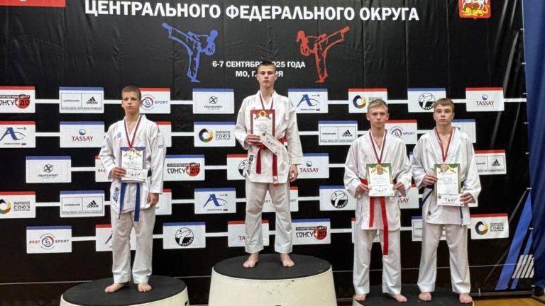 Спортсмен на пьедестале с дипломом и медалью по каратэ